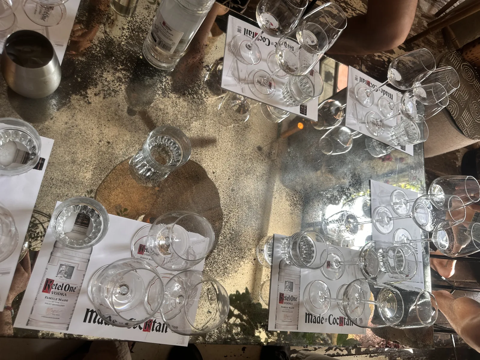 The Ketel One cata — glassware and 'Made to Cocktail' sheets across a mercury-spotted mirror table.