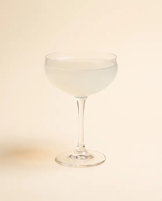 Daiquiri — a coupe with a pale, clear cocktail and a lime wheel, on a cream background